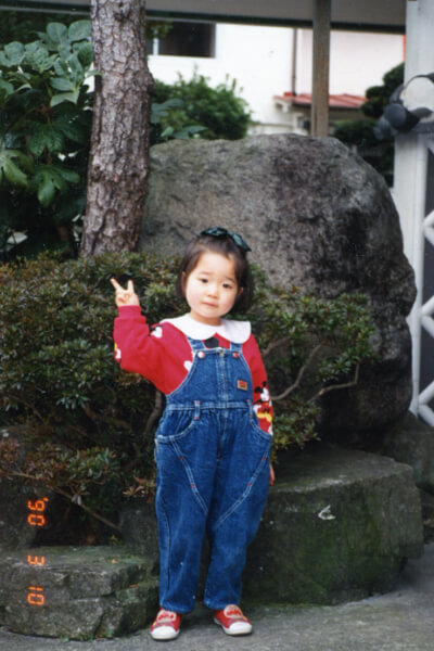 ４歳の頃、笑顔でカメラにピースする川島あいさん